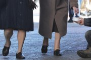 Dos mujeres depositan una limosna a una persona que pide en la calle.-ISRAEL L. MURILLO
