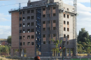 Una mujer y un niño  pasan por delante de un edificio en obras.-ISRAEL L. MURILLO
