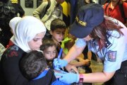 Una agente de policía checa escribe el número en la mano de un niño.-AP/IGOR ZEHL