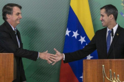 El presidente de Brasil, Jair Bolsonaro (izquierda), y el líder opositor y autoproclamado presidente venezolano, Juan Guaidó, se saludan durante el encuentrpo que mantuvieron este jueves en Brasilia.-SERGIO LIMA (AFP)
