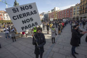 Una persona sostiene un cartel exigiendo compensaciones económicas durante una protesta contra los cierres de hostelería decretados por la Junta. S. OTERO