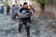Un hombre traslada a un niño herido en el bombardeo sobre una escuela en Alepo.-Foto: REUTERS/ HOSAM KATAN