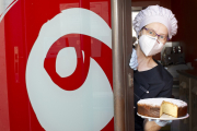 Carol se asoma a la puerta de su tienda obrador con uno de sus bizcochos.- SANTI OTERO