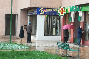 Compradores hacen cola frente a una farmacia esta mañana bajo la lluvia esperando a ser atendidos, dejando más de un metro de distancia. S. L. C.