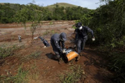 Bomberos cargan uno de los cadáveres recuperados el 12 de noviembre tras la rotura de la represa de la mina de hierro.-REUTERS / RICARDO MORAES