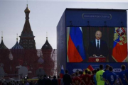 Un grupo de funcionarios y jugadores de fútbol miran el discurso televisado del presidente ruso, Vladimir Putin, en la Plaza Roja de Moscú, este viernes.-AP