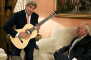 Kerry con la guitarra española que le ha regalado Margallo, sentado en el sofá, esta tarde en el Palacio de Viana, en Madrid.-EFE / BALLESTEROS