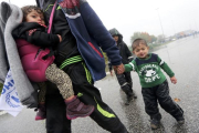 Un hombre camina llevando a dos niños bajo la lluvia junto a la frontera con Eslovenia.-SRDJAN ZIVULOVIC / REUTERS