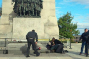 Unos soldados atienden a un compañero herido, ante el monumento de los veteranos de guerra en Ottawa.-Foto: EL PERIÓDICO