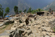 Nepalís caminan entre escombros de casas en la localidad de Ungul, a 60 kilómetros de Katmandú, el lunes.-Foto: AFP / PRAKASH MATHEMA