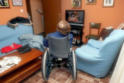 Una anciana en silla de rueda ve la televisión en su domicilio.-MONTSE ÁLVAREZ