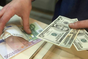 Euros y dólares en las manos.-Foto: ARCHIVO/ AFP