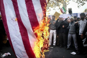 Manifestantes queman la bandera.-REUTERS