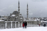 Varios transeúntes caminan por un nevado puente de Galata, en Estambul, este miércoles.-Foto: AFP / BULENT KILIC