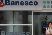 Una mujer espera frente a una oficina del banco Banesco en Caracas.-/ AFP / LUIS ROBAYO