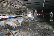 Los bomberos trabajan, junto a los coches calcinados, para comprobar el estado de las instalaciones. / RAÚL G. OCHOA