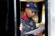 Un polícía de Caracas lee la ley de amnistía distribuida por la oposición.-EL PERIÓDICO