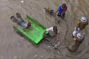 Lecheros intentan abrirse paso por una calle inundada tras las fuertes lluvias en Allahabad, India.  /-RAJESH KUMAR SINGH (AP)