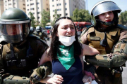 Dos agentes antidisturbios detienen a una joven manifestante en Santiago de Chile.-PABLO VERA (AFP)