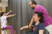 Un fisioterapeuta asite a una usuaria que realiza ejercicios de rehabilitación.-ICAL
