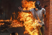 Un manifestante entre llamas después de estallar el depósito de la moto de un policía durante una protesta contra el presidente Maduro en Caracas.-AFP /JUAN BARRETO