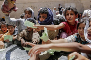 Niños yemenís presentan documentos para recibir las raciones de alimentos proporcionadas por una oenegé local en Saná.-HANI MOHAMMED (AP)