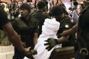 Habré, completamente tapado con una vestimenta blanca, rodeado de policías en el tribunal, en Dakar, este lunes.-Foto: AFP / SEILLOU