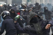 Manifiestantes antisistema lanzan botellas contra la policía italiana en Milán.-Foto: AP / DANIEL DAL ZENARO