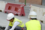 Dos trabajadores en cuclillas colocan nuevas baldosas en una acera.-ISRAEL L. MURILLO