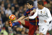 Varane y Luis Suárez luchan por un balón en el clásico del pasado año en el Bernabeú.-AP / FRANCISCO SECO