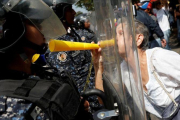 Una manifestantes de la oposición se encara con los antidisturbios en la protesta de este sábado en Caracas.-REUTERS / CARLOS GARCÍA RAWLINS