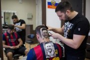 Mario Hvala, en plena tarea de esculpir el retrato de Messi en la cabeza de un seguidor del Barça de Novi Sad.-/ AFP