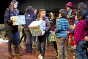 En la imangen voluntarios de CaixaProinfancia entregan regalos a un grupo de niños y niñas.-ECB