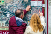 Dos turistas consultan uno de los mapas de la ciudad de Burgos instalado en un Mupi.
