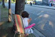 Una mujer espera sentada en una silla de playa para ver el concierto de Raphael.
