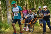 Uno de los participantes con una silla joëlette acompañado de otros inscritos en la prueba.