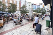Un joven arrastra sus maletas junto a una terraza del centro.