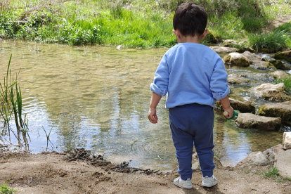 Un niño juega junto a un río.