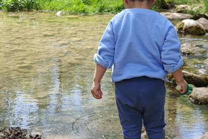 Un niño juega junto a un río.