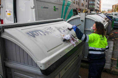 Una operaria de Urbaser limpia una pintada en un contenedor.