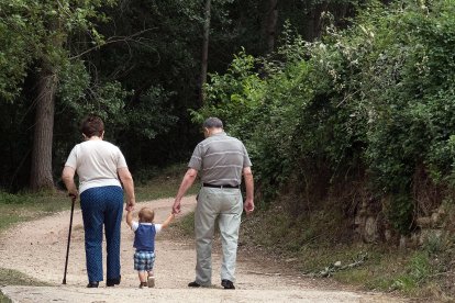 Un niño camina de la mano de dos personas mayores. TOMÁS ALONSO