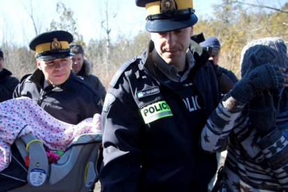 Una madre y su bebé escoltados por la policía montada de Canadá en la frontera de EEUU y Quebec.-CHRISTINNE MUSCHI