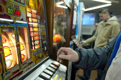 Varias personas gastan dinero en máquinas tragaperras en un local destinado a las apuestas y juegos de azar.-ICAL