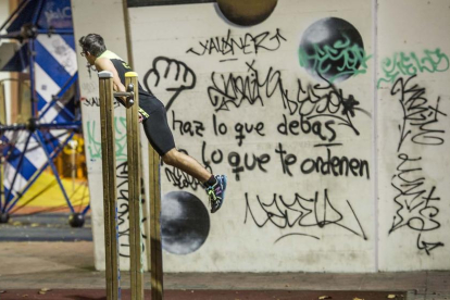 Un joven se ejercita en el parque bajo la autovía, un lugar que es objeto de la acción de los vándalos que han pintado las columnas.-ISRAEL L. MURILLO