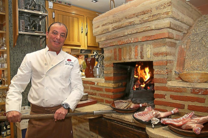Alberto Sánchez, propietario del restaurante La Encina, se dispone a asar unos cuartos de lechazo.-BRÁGIMO