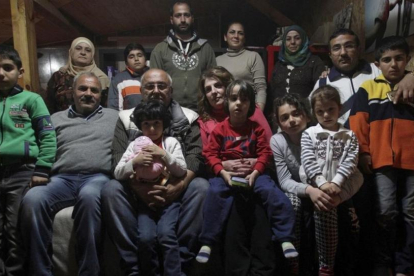 Dimitris Spiridis (en primera fila, tercero por la izquierda), junto a su mujer, Maria, y varios miembros de las dos familias sirias que acoge en su casa, en Evropos, cerca de Idomeni, este lunes.-REUTERS / ALEXANDROS AVRAMIDIS