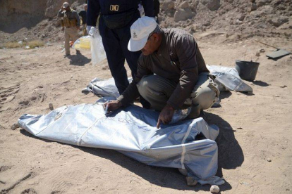 Un forense del ministerio iraquí de Sanidad escribe un número en la bolsa donde se ha colocado uno de los cadáveres localizados en fosas comunes en Tikrit.-Foto: STRINGER / REUTERS