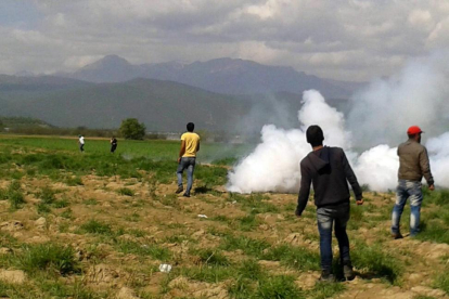 La guardia fronteriza macedonia lanza gases lacrimógenos contra los refugiados que intentaban cruzar la frontera desde Idomeni, este domingo.-EFE