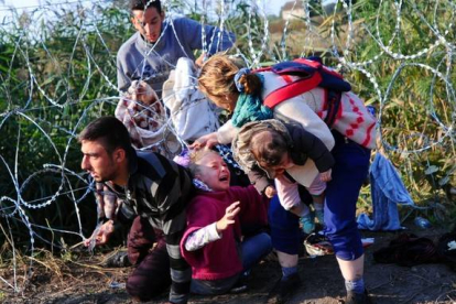 Una joven refugiada llora al quedársele el cabello enganchado en las púas de la concertina de la frontera de Hungría con Serbia.-AFP / ATTILA KISBENEDEK