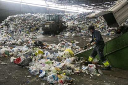 Un empleado trabaja con residuos en las instalaciones de la planta de tratamiento y selección de envases de Gavà, para su posterior reciclaje.-JOAN PUIG